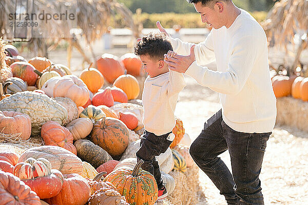 Father and son climbing through hay and pumpkins