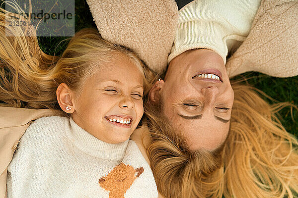 Mother and daughter having fun lying in the grass