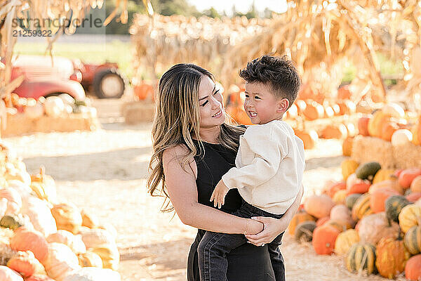 Mother holding son in the middle of a pumpkin patch