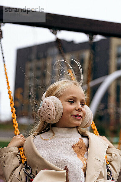 Young girl long hair playing on swing sunny yard