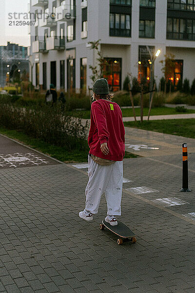 A young woman rides a skateboard along the city streets