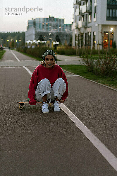 A young woman rides a skateboard along the city streets