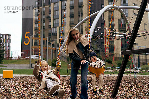 Brother and sister play on the swings at playground