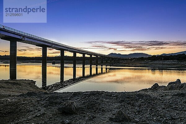 Silhouette der Brücke über den Fluss bei Sonnenuntergang mit Reflexionen auf dem Wasser