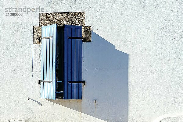 Altes Fenster mit hölzernen blau gestrichenen Fensterläden auf weiß gestrichener Wand