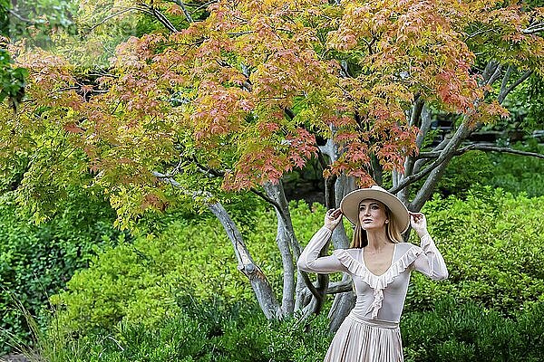 Ein umwerfendes Model präsentiert Herbstmode inmitten der Schönheit der Natur und verströmt Eleganz und Charme in einem malerischen Park