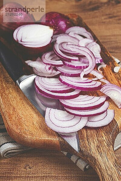 In Scheiben geschnittene rote Zwiebel  auf einem Schneidebrett  mit einem Messer  spanische Zwiebel  rohe Zwiebel  Nahaufnahme  Draufsicht