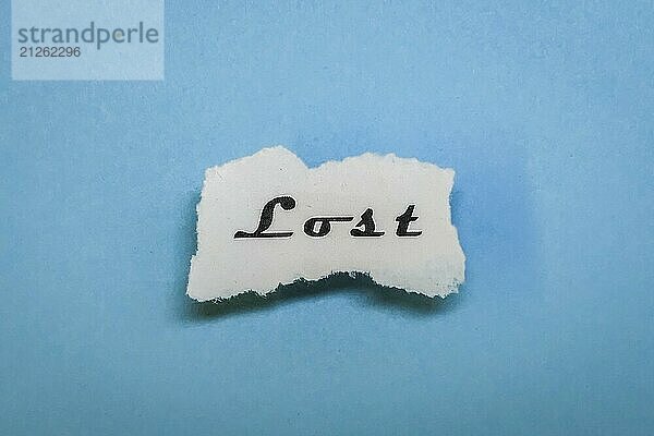 Ein Stück Papier mit dem Wort 'Lost' auf blauem Hintergrund  minimalistisch