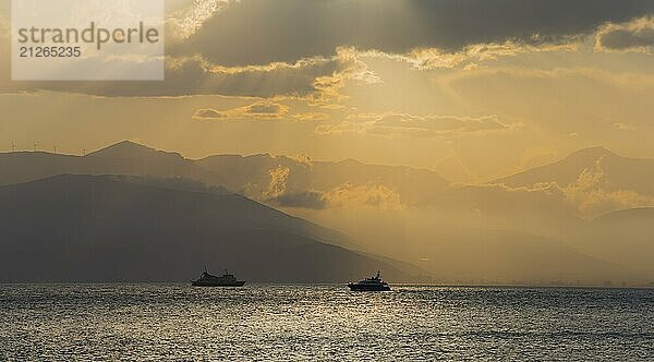 Dramatischer Sonnenuntergang über dem Meer mit Bootssilhouetten und wolkigem Himmel  Agia Kyriaki  Nafplio  Nauplia  Nauplion  Nafplion  Argolis  Argolischer Golf  Peloponnes  Griechenland  Europa