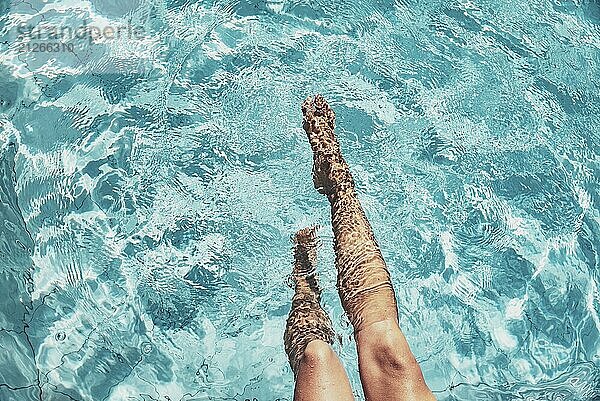 Zwei im Wasser schwebende Beine in einem klaren  blauen Pool