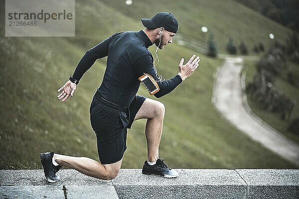 Junger kaukasischer männlicher Jogger mit einem am Arm befestigten Fitness Tracker beim Aufwärmen vor dem Joggen