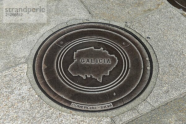 Metallgullydeckel mit der Aufschrift 'Galicia' und Umriss einer Karte  Gullideckel  Gullydeckel  Santiago de Compostela  autonome Gemeinschaft Galicien  Wallfahrtsort  Ziel des Jakobswegs  Spanien  Europa