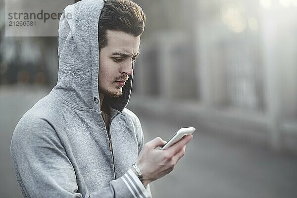 Glücklicher Teenager  der auf der Straße geht und ein Smartphone benutzt