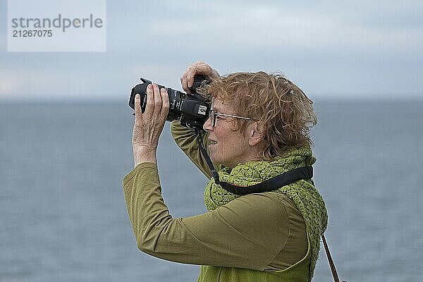 Ältere Frau fotografiert mit Spiegelreflex-Kamera  Wattenmeer  Nordfriesland  Schleswig-Holstein  Deutschland  Europa