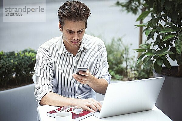 Kluge Einstellung. Positiver gutaussehender Mann  der einen Laptop benutzt und im Cafe sitzt  während er im Internet surft