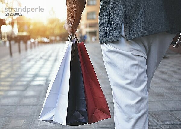 Nahaufnahme eines jungen kaukasischen Mannes  der auf der Straße verschiedene Einkaufstüten aus Papier hält