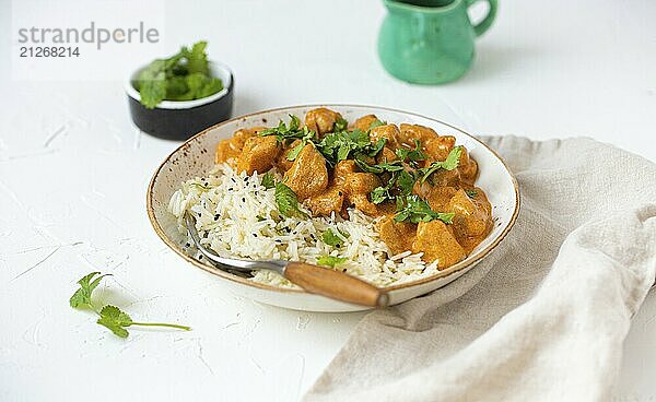 Traditionelles indisches Gericht Hühnercurry mit Basmatireis und frischem Koriander auf rustikalem weißen Teller auf weißem Beton Küchentisch  Nahaufnahme mit selektivem Fokus. Indisches Abendessen  Food Fotografie  food photography