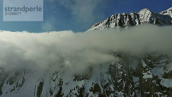 Fliegen durch schöne weiße flauschige Wolken zwischen hohen felsigen Bergen. Dolomiten Alpen Berge  Italien  Europa