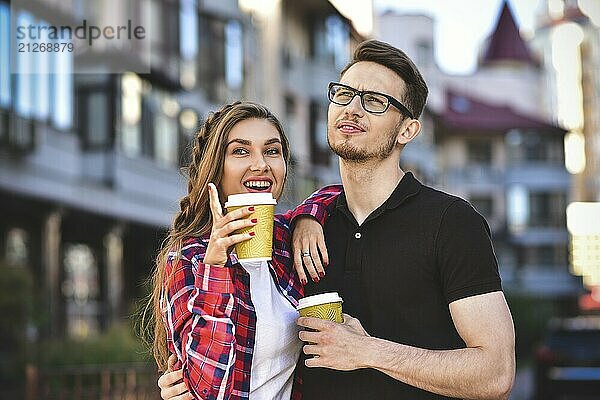 Porträt eines glücklichen Paares  das mit Kaffee auf der Straße spazieren geht