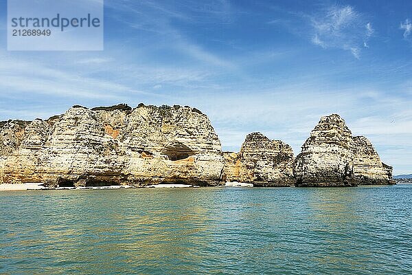 Atemberaubende Felsformationen an der Küste von Lagos in Portugal erheben sich majestätisch aus dem klaren türkisfarbenen Wasser unter einem strahlend blauen Himmel und verkörpern die Schönheit und Ruhe einer unberührten Naturlandschaft