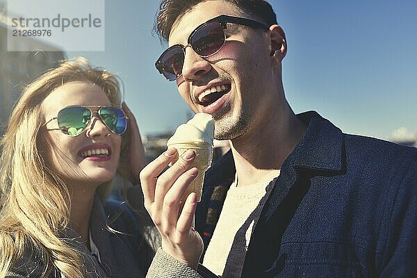 Glückliches romantisches kaukasisches Paar mit Sonnenbrille. Lustige Mädchen essen das Eis