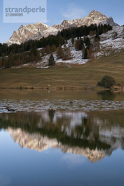 Blick über den Taraspsee auf einige Berggipfel  die in der späten Abendsonne leuchten