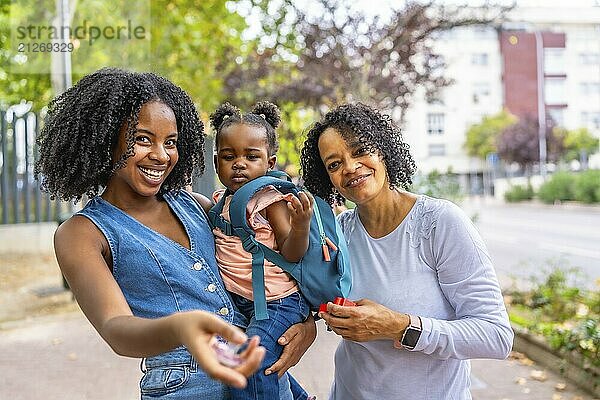 Porträt einer drei Generationen umfassenden afrikanischen Familie im Park  die lächelnd vor der Kamera zusammensteht