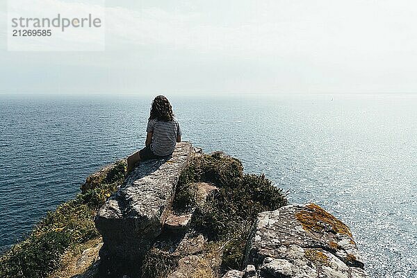 Schöne Frau auf den Klippen mit Blick auf das Meer in der Gegend von Cap Frehel  Bretagne  Frankreich. Atlantischer Ozean Französische Küste