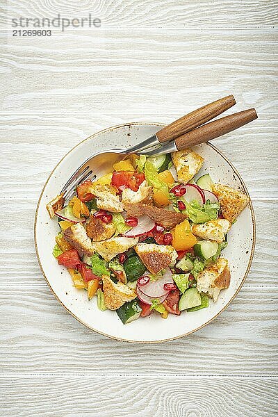 Traditionelle Levante Gericht Fattoush Salat  arabische Küche  mit Fladenbrot Croutons  Gemüse  Kräuter. Gesunder vegetarischer Salat aus dem Nahen Osten  rustikaler hölzerner weißer Hintergrund von oben  Lebensmittel Fotografie  food photography  food photography