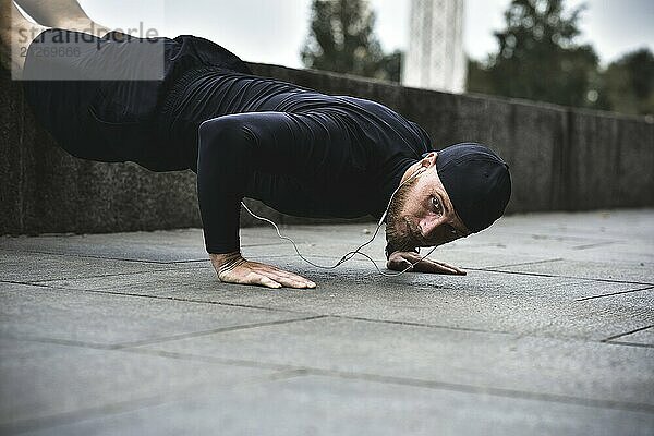 Junger bärtiger Sportler macht Workout in einem Park  macht eine Reihe von Push ups im Freien