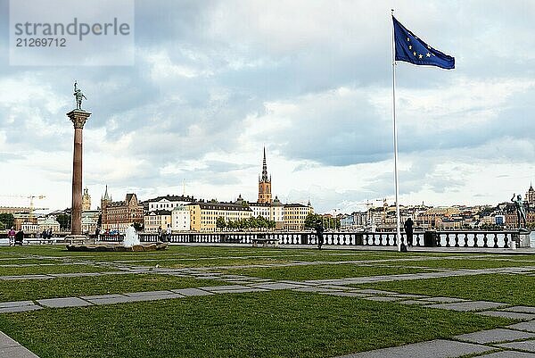 Stockholm  Schweden  9. August 2019: Stadtbild von Stockholm und der Insel Riddarholmen vom Garten des Rathauses mit wehender Europaflagge. Blick bei Sonnenuntergang  Europa