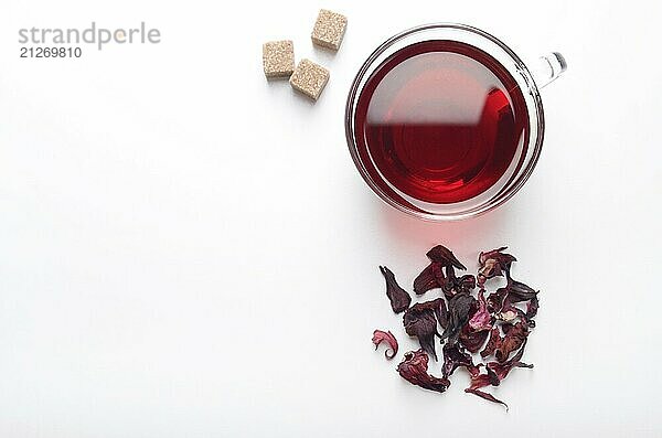 Draufsicht auf Hibiskus Tee Tasse mit Blütenblättern und Zuckerwürfeln auf weißem Hintergrund