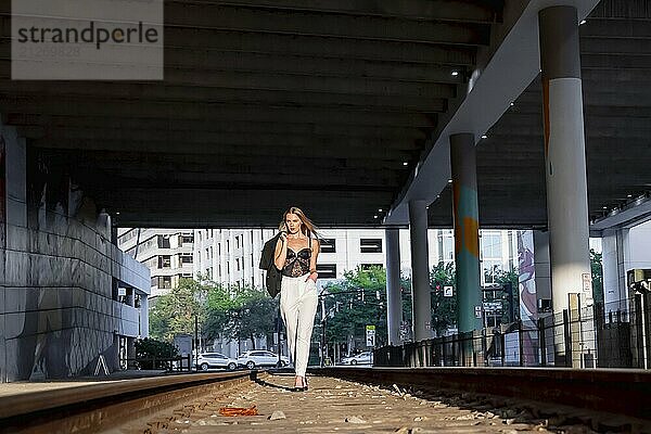 Ein wunderschönes blondes Modell posiert bei Sonnenuntergang auf Bahngleisen