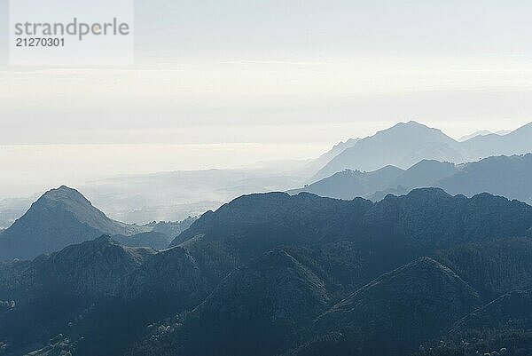 Panoramablick auf Silhouetten von Bergen im Morgennebel mit schneebedeckten Bergen im Hintergrund. Picos de Europa  Asturien  Spanien  Europa