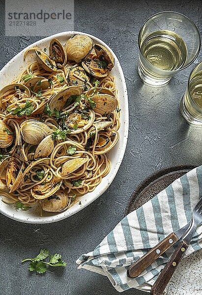 Lebensmittel  Meeresfrüchte Nudeln. ITALIENISCHE SPAGHETTI ALLE VONGOLE. Venusmuscheln Spaghetti auf weißem Teller mit Weißwein  grauer Hintergrund. Ansicht von oben