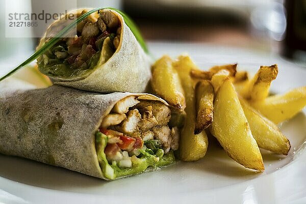 Leckere Wraps mit Hähnchen  Avocado  Salat und Pommes frites auf einem Teller. Selektiver Fokus