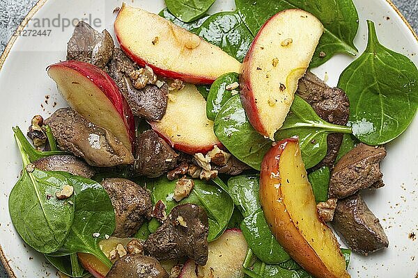 Close Up of Healthy Salad with Iron Rich Ingredients Hühnerleber  Äpfel  frischer Spinat und Walnüsse auf weißem Keramikteller Draufsicht  food photography