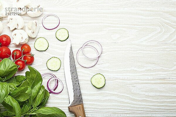 Lebensmittel Kochen Hintergrund: frische Zutaten mit Küchenmesser  Basilikum  Kirschtomaten  Pilze  schneiden Gurken und Zwiebeln auf weißem Holz Hintergrund von oben gesehen. Mahlzeit Vorbereitung Vorlage  Platz für Text  Lebensmittel Fotografie  food photography