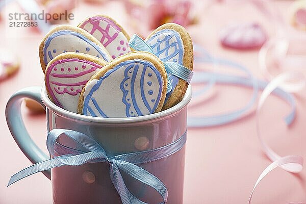 Ostern Backen Hintergrund der gefrosteten Cookies in Form von Ei in blauen Becher auf rosa Hintergrund