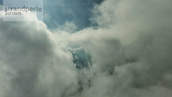 Fliegen durch schöne weiße flauschige Wolken zwischen hohen felsigen Bergen. Dolomiten Alpen Berge  Italien  Europa