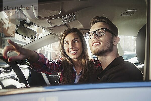 Genießen Sie die Reise. Schönes junges Paar sitzt auf dem Beifahrersitz und lächelnd  während gut aussehende Mann fährt ein Auto