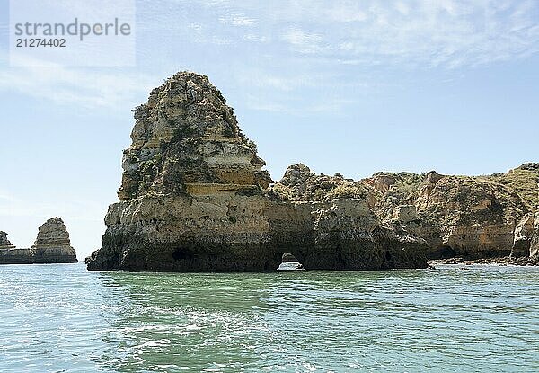 Atemberaubende Felsformationen an der Küste von Lagos in Portugal erheben sich majestätisch aus dem klaren türkisfarbenen Wasser unter einem strahlend blauen Himmel und verkörpern die Schönheit und Ruhe einer unberührten Naturlandschaft