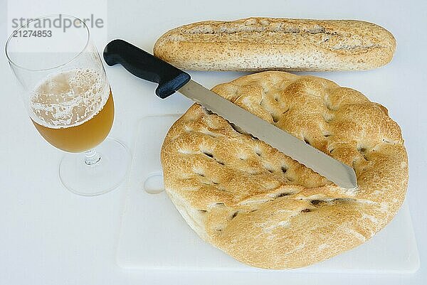 Laib Brot  Bier und Messer auf weißem Tisch  Lebensmittel in Großaufnahme Ansicht von oben