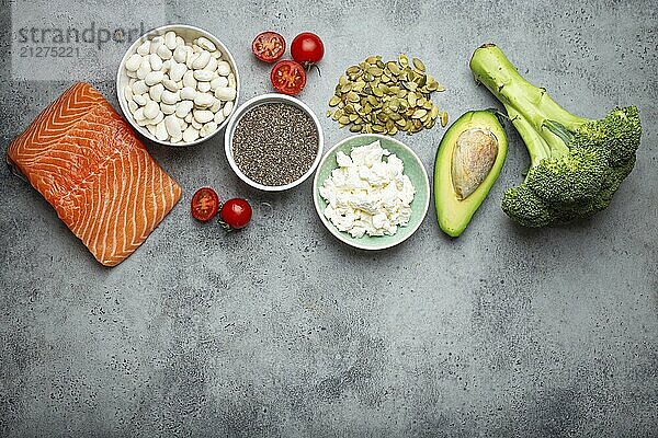 Auswahl an gesunden Lebensmitteln  wenn eine Person Diabetes hat: Lachs  Fisch  Brokkoli  Avocado  Bohnen  Gemüse  Samen auf grauem Hintergrund von oben. Gesunde Diabetes Diät  Lebensmittel Fotografie