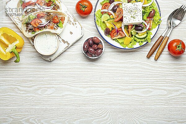 Traditionelles griechisches Essen: Griechischer Salat  Gyros mit Fleisch und Gemüse  Tzatziki Sauce  Oliven auf weißem rustikalen Holztisch Hintergrund von oben. Griechische Küche. Textfreiraum  Lebensmittel Fotografie  food photography  food photography