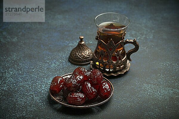 Fastenbrechen mit getrockneten Datteln während des Ramadan Kareem  Iftar Mahlzeit mit Datteln und arabischem Tee im traditionellen Glas  Blickwinkel auf rustikalem blauen Hintergrund. Muslimisches Festmahl  Foodfotografie  food photography  food photography