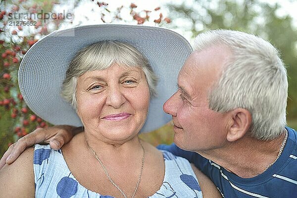 Authentische Außenaufnahme eines alternden Paares  das Spaß im Garten hat und mit Liebe gesegnet ist. Während ihres Spiels versucht der Mann  seine Frau zu küssen und sie lächelt. Liebe und Familie Konzept