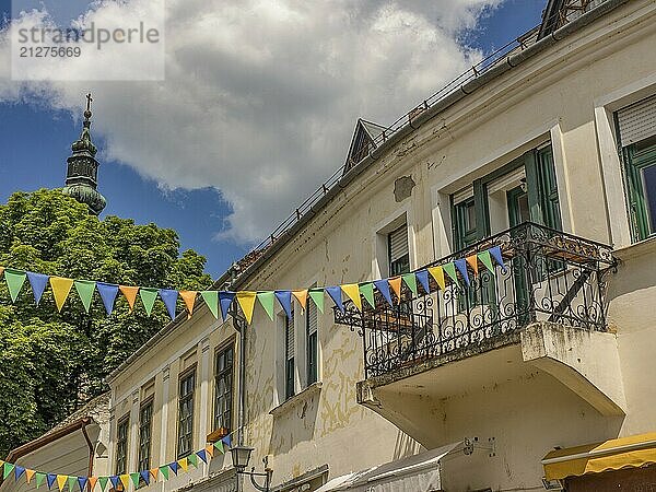 Fröhliche Dorfstraße mit weißen Gebäuden und bunten Girlanden unter einem klaren blauen Himmel  esztergom  donau  ungarn