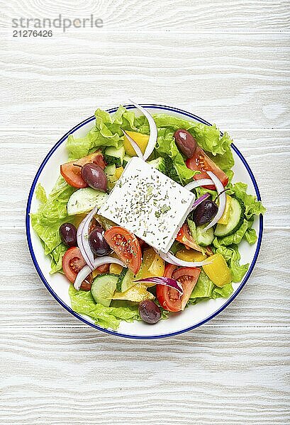 Traditioneller griechischer Salat mit Feta Käse  Tomaten  Paprika  Gurken  Oliven  Kräutern in weißer Keramikschale auf weißem rustikalem Holztisch Hintergrund von oben  Griechische Küche  Foodfotografie  food photography  food photography