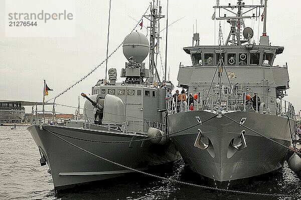 Zwei graue Marineschiffe im Hafen mit Menschen an Bord und Flaggen im Hintergrund  kopenhagen  dänemark